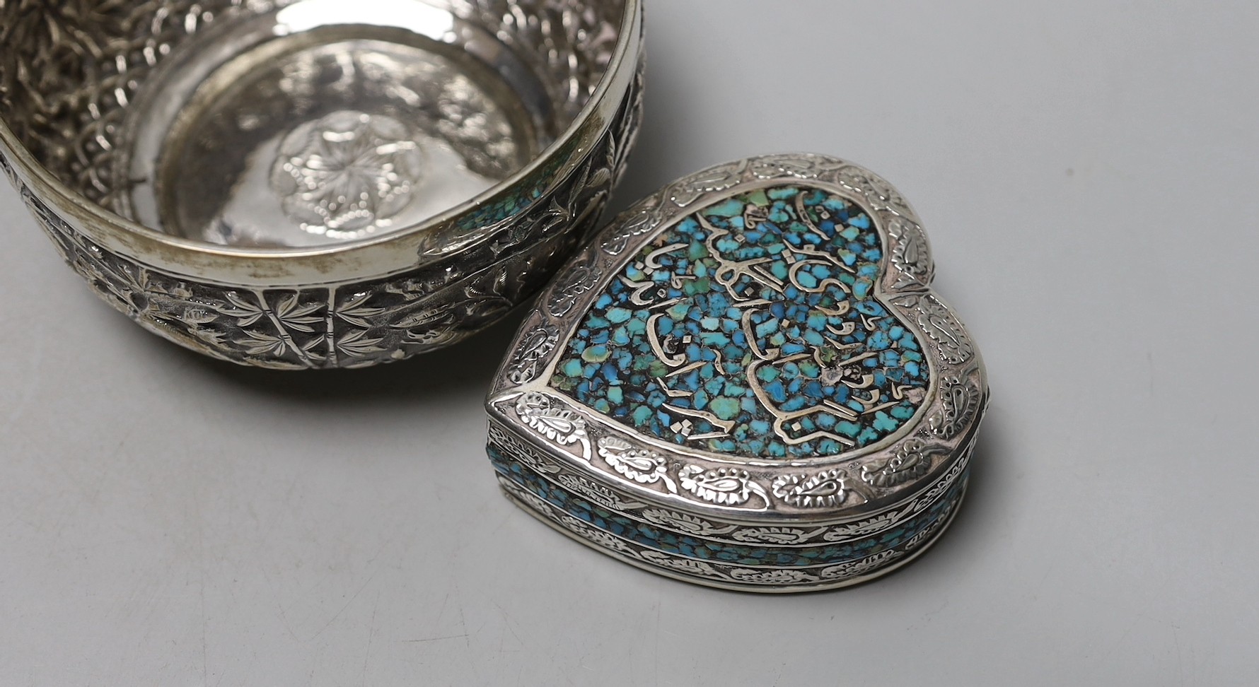 A pair of Indian embossed white metal finger bowls, diameter 97mm , a Persian white metal and turquoise set heart shaped paperweight and an Indian white metal and turquoise set heart shaped box.